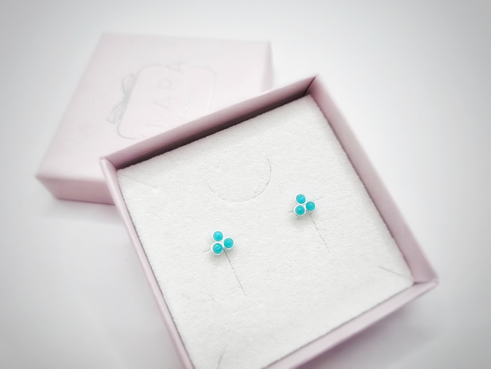 A pair of green opal stud earrings featuring three semi-precious dots, representing the December birthstone